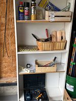 Wide shot of shelving with assorted tools, paintbrushes, paint rollers, and cans including WD-40