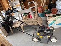 Full view of lawn mower showing handle, wheels, and body in garage setting.
