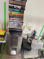 DVD player with Oritron subwoofer and five speakers along with DVDs stacked on and around them