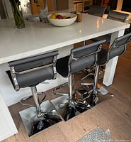 Three adjustable chairs under white island counter