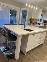 Front left perspective of island showing granite countertop, integrated sink and faucet with seating area