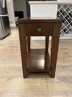 Front view of the wooden side table showing the drawer and lower shelf.
