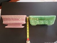 Two pottery planters on black background with measuring tape showing approximately 8 inches length.