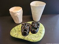 Three ceramic items shown: Leedsware Classic Creamware vase, Arabia Finland white floral embossed vase, and Marcia of California covered candy dish with theatrical mask design.