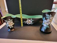 Front view of 3 pieces of Herta pottery showing the Dogwood floral design on black glaze with soft green interior, with a measuring tape indicating 6 inches height for the vases
