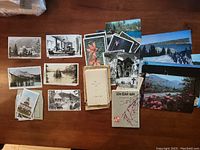 Multiple assorted postcards laid out on a flat surface showing varied scenic views and subjects including flowers and buildings.