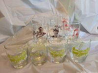 Shot showing 10 souvenir glasses with various British Columbia themed prints including bright yellow, dark and red designs