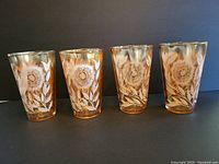 Set of four vintage drinking glasses, showing iridescent gold tint and white floral designs
