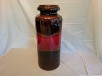 Front view of the tall pottery vase showing the lava glaze finish in brown and red.
