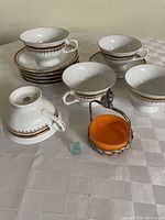 Five demitasse cups and matching saucers stacked and arranged with small basket and figurine