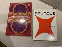 Two books including 'Designs and Patterns from Historic Ornament' with a red patterned cover and 'Bauhaus 1919-1928' with a white cover and orange design.