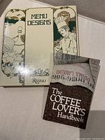 Two books shown: 'Menu Designs' by Rizzoli with illustrated cover, and 'The Coffee Lover's Handbook' with coffee beans cover.
