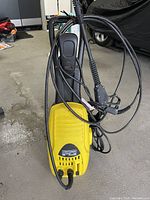 Front view of yellow Craftsman CPW 1500 power washer, hoses and spray gun coiled around unit, showing overall condition and attached components.