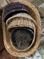View of 4 woven baskets nested inside each other showing various sizes and colors including burgundy, gray, and natural 13" diameter baskets inside a large oval dog basket.