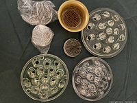 Overview photo displaying different sizes and shapes of flower frogs made of glass and metal.