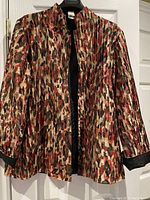 Women’s multicolor patterned jacket with pleated texture, stand collar, and cuffed sleeves with black trim.