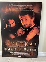 Full view of Molokai movie poster mounted on board showing main characters and text details