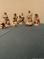 Wide shot showing all nativity set figurines arranged on a teal cloth.