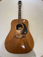 Full front view of vintage dreadnought acoustic guitar showing body shape, spruce top, pickguard logo, fretboard inlays