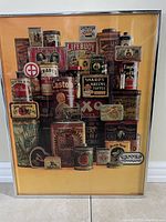 Full view of framed poster showing a collage of vintage product tins with brand names and colorful old-style packaging.