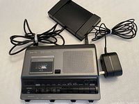 Top view of the Sanyo Memo-Scriber cassette recorder with attached power cables and charger