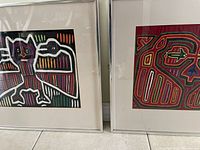 Photo of two framed Panamanian Molas placed side by side showing colorful bird motif designs on fabric.