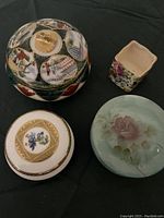 Top view of four vintage trinket and powder jars showing different shapes, colors and decorations including floral and Japanese motifs.