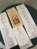 Photo showing multiple paper sewing patterns for baby bibs with animal names on the front, including Pig, Duck, Turtle, Sheep, Cow, Koala, Penguin, Turkey, Ostrich, Skunk, Mouse, Kangaroo, Flamingo.