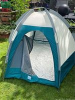 Tent pitched outdoors showing the front entry with the door open, displaying interior groundsheet and spacious interior.