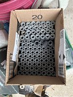 Box filled with 125 cylindrical lead and zinc concrete anchors with hollow centers.