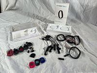 Overview of Fitbit devices, bracelets, chargers, and packaging on white sheet showing full lot contents