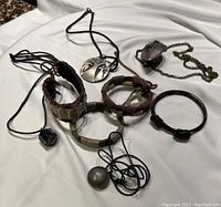 Full view of all jewelry pieces including 4 bracelets and 4 necklaces on white fabric background. Provides overall view of lot contents and condition.