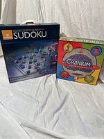 Photo showing boxed Stokke Sudoku glass game and Cranium board game boxed set.