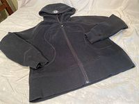 Black Lululemon zip-up hoodie laid flat showing front with full zipper and hood.