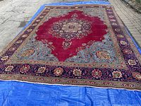 Full view of rug laid out on tarp and pavement