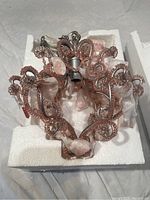 Chandelier in its original foam packaging showing the metal frame and pink crystals.