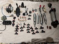 Overview of pneumatic components laid out on a towel showing cylinders, valves, fittings and connectors