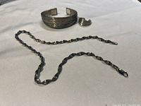 Overview of all three pieces: necklace, cuff bracelet and ring arranged on table