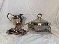 Full view of the three silver plated items: pitcher, covered server, butter dish with lid and glass insert