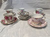 Front view showing six teacups on saucers with various floral designs and gold trim detailing.