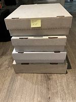 Four white hobby boxes stacked closed, containing hockey cards inside.