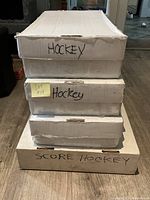 Four large white cardboard boxes stacked; three labeled 'Hockey' and one labeled 'Score Hockey'. Boxes contain hockey sports cards.