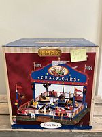 Box front showing Lemax Crazy Cars carnival ride from Village Collection with detailed image of the miniature ride on the box front.