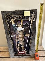 Front view of statue in box with visible measuring tape showing height and packaging detail including sculptor's name Randy Bowen.