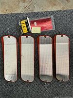Four reflective rectangular salmon fishing flashers laid flat on a carpet, showing the front metallic surfaces and red or orange borders, with metal clips on top and holes on bottom for line attachments. A small note marked 'Lot of 5' is present.