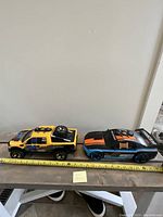 Side view of both toy vehicles placed on a surface with a measuring tape showing approximately 13 inches long