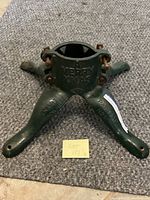 Front angle of the green cast iron Christmas tree stand showing three legs and embossed text including 'A MERRY XMAS','SMART BROCKVILLE', and 'PAT. 1931 No 1'.
