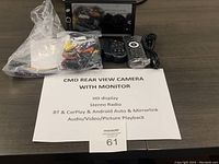 CMD rear view camera system components displayed on table including monitor, remotes, cables, and manual.