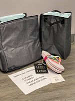 Two grey insulated cooler bags with light blue Leak Lock liners, one pair of rainbow strap flip flops, and LCBO gift card with information sheet on floor
