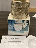 Image of white birch log planter on its box showing natural bark texture. Paper items nearby describing the planter.